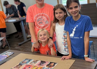 Four people smile around a completed puzzle on a table, with colorful animal illustrations.