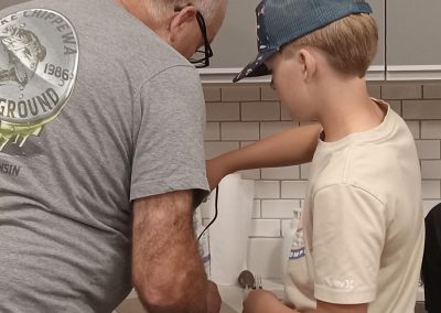 An older person and a younger person working on the airplane craft together.