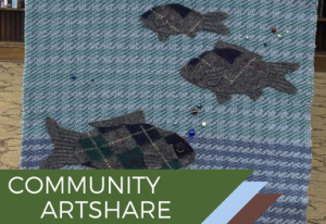 Woven textile artwork with three stylized fish on a blue patterned background and a bottom banner reading “COMMUNITY ARTSHARE.”